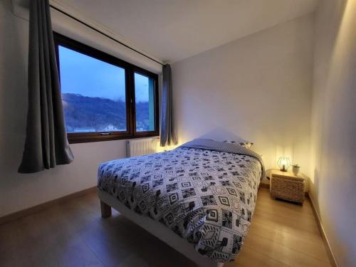 une chambre avec un lit et une grande fenêtre dans l'établissement Charmant appartement T2 à Ugine, à Ugine