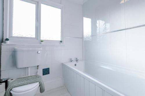 baño blanco con bañera y aseo en Delighful Family House in Stalybridge Sleeps 9 with WiFi by PureStay, en Stalybridge