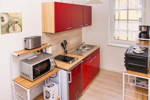 una piccola cucina con armadi rossi e forno a microonde di Loftartiges Appartment in Magdeburg, 2 Schlafzimmer, Küche und Bad - B a Magdeburgo