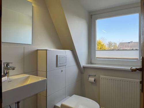 ein Badezimmer mit Waschbecken und Toilette und einem Fenster in der Unterkunft Haus am Südende Nordsee in Westerland