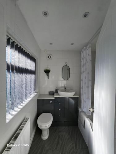 biała łazienka z toaletą i umywalką w obiekcie By the Joyous Stays w mieście Stoke-on-Trent