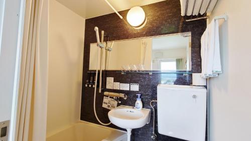 małą łazienkę z umywalką i lustrem. w obiekcie Pension and Restaurant La Collina w mieście Nakafurano