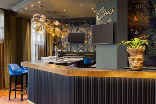 a bar in a hotel lobby with a counter at Amedia Hotel & Suites Leipzig, Trademark Collection by Wyndham in Leipzig