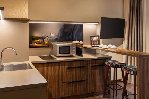 a kitchen with a sink and a microwave on a counter at Amedia Hotel & Suites Leipzig, Trademark Collection by Wyndham in Leipzig
