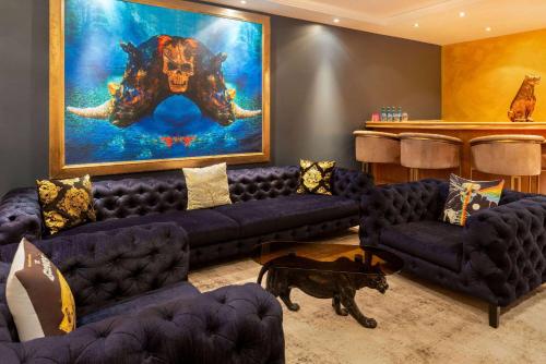 a living room with blue couches and a painting at Amedia Hotel & Suites Leipzig, Trademark Collection by Wyndham in Leipzig