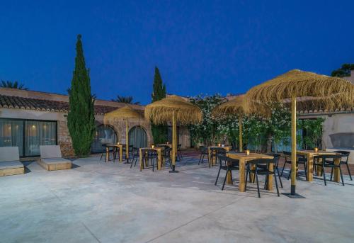a group of tables and chairs with straw umbrellas at Alqueria de Vilches in Cullera