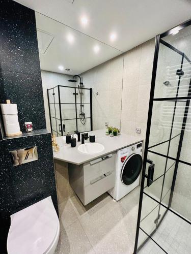 a bathroom with a sink and a washing machine at Apartment Targowa L7 in Lublin