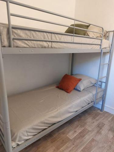 - un lit superposé avec un oreiller orange sur la couchette inférieure dans l'établissement Location de vacances, à Canet