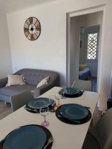 - une table à manger avec des assiettes et des verres à vin dans l'établissement Location de vacances, à Canet