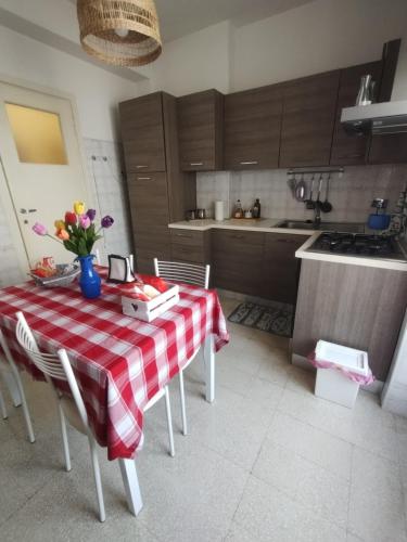 Appartamento Fiore Roma Cinecittà في روما: مطبخ مع طاولة مع قماش طاولة حمراء وبيضاء