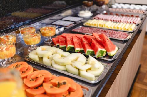a buffet of food with fruits and vegetables on trays at Hotel Petrópolis in Nova Petrópolis
