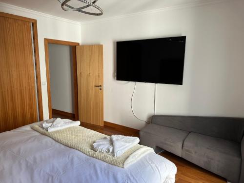a bedroom with a bed with a couch and a flat screen tv at NICE and MODERN FLAT NEAR AIRPORT in Santa Cruz