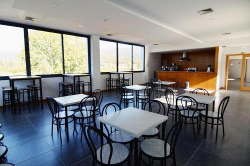 a restaurant with tables and chairs in a room with windows at Bed & Breakfast EQUITARE RURAL in Miranda do Corvo