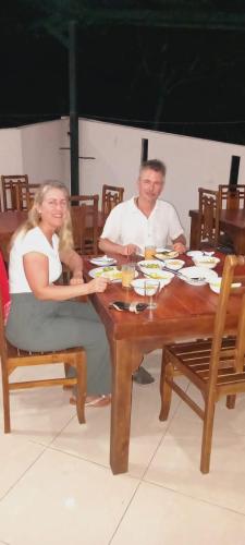 a man and a woman sitting at a wooden table at Kandy IVY Mountain View Resort in Kandy