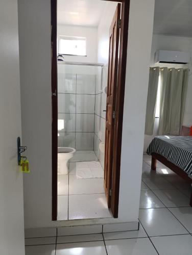 a bathroom with a toilet and a glass door at Hotel Monte Arau in Boa Vista