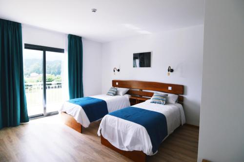 2 camas en una habitación con ventana grande en Bed & Breakast EQUITARE RURAL, en Miranda do Corvo