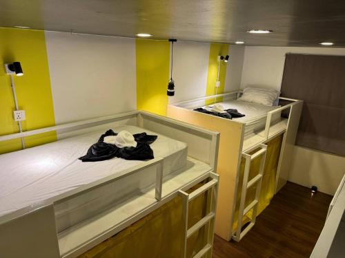 2 Betten in einem Zimmer mit gelben Wänden in der Unterkunft The Hive Hotel in Siem Reap