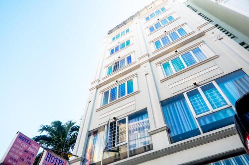 a white building with blue windows and a palm tree at CÁT PHÚC HOTEL in Ho Chi Minh City