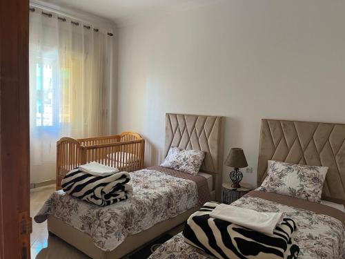 1 dormitorio con 2 camas, silla y ventana en Cozy appartement Tanger en Tánger