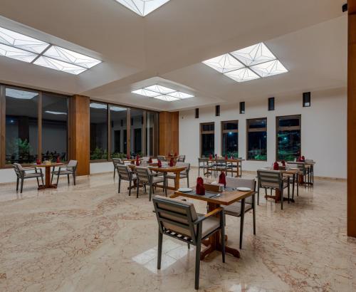 a dining room with tables and chairs and windows at Highland Club with Swimming Pool-GYM in Kolhapur