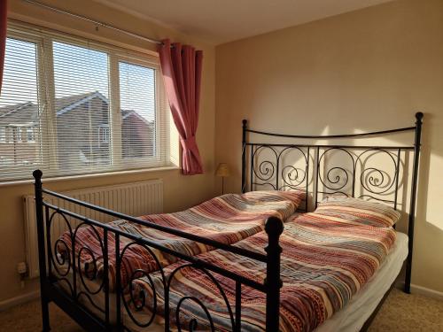 1 cama negra en un dormitorio con ventana en Isis Guest House en Sunningwell