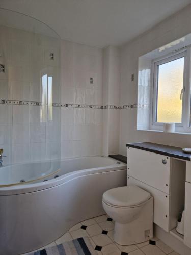 een witte badkamer met een bad en een toilet bij Isis Guest House in Sunningwell