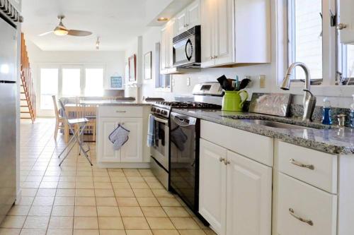 a white kitchen with a sink and a stove at Cheerful 3 Bedroom Beach Front Cottage with Fire Place in Milford