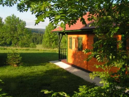 a small house in the middle of a field at Camping-Chalets La Favière in Lac des Rouges Truites