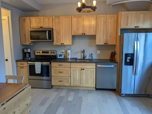 a kitchen with wooden cabinets and a stainless steel refrigerator at Condo at The Commons in Traverse City