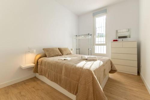 ein Schlafzimmer mit einem Bett in einem weißen Zimmer in der Unterkunft Elegante y nuevo apartamento junto al Palacio Congresos in Sevilla