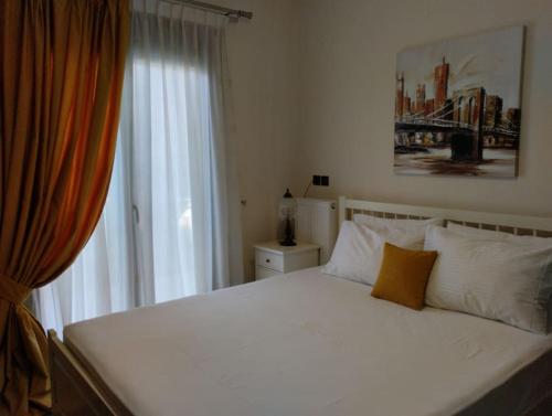 ein Schlafzimmer mit einem weißen Bett und einem Fenster in der Unterkunft XΡΗΣΤΟΣ house in Ioannina