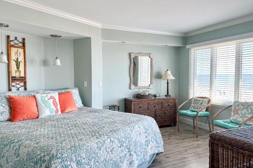 a bedroom with a bed and a chair and a mirror at Port O'Call B-301 in Isle of Palms