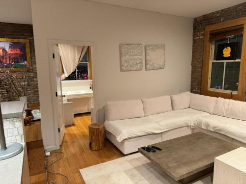 uma sala de estar com um sofá branco e uma mesa em Tribecca Modern Brick Wall 3BR 2BA em Nova York