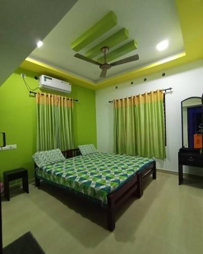 a bedroom with a bed in a room with green walls at Heaven Homestay in Alleppey