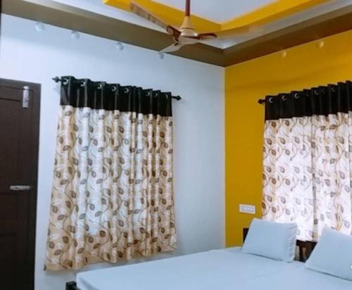 a bedroom with curtains and a bed with white sheets at Heaven Homestay in Alleppey