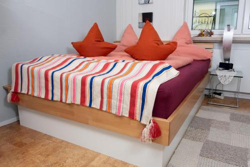 ラインバッハにあるBirgits Lodgeのベッド(オレンジ色の枕、カラフルな毛布付)