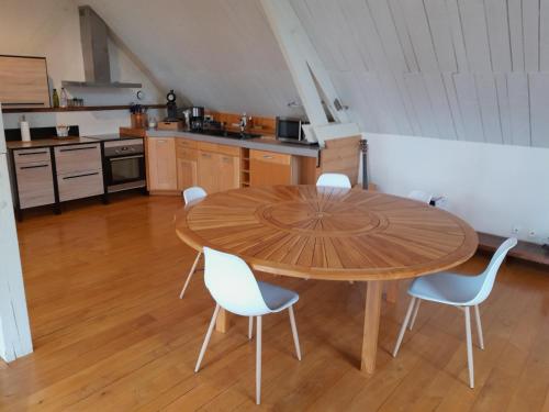 a kitchen with a wooden table and white chairs at la maison dans les bois in Soucelles