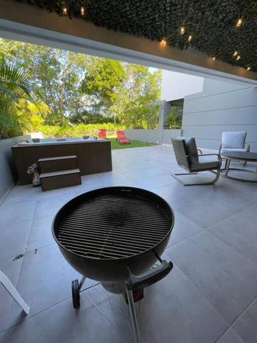 a grill on a patio with chairs and a table at Apartamento de lujo en playa in Playa del Carmen