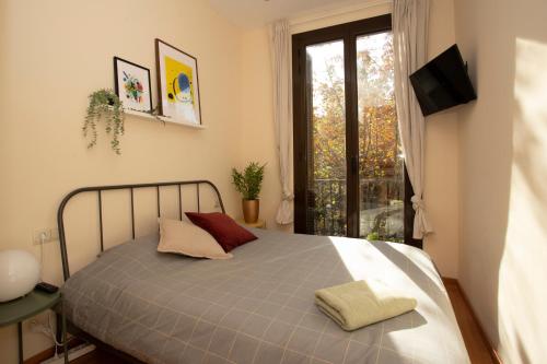 um quarto com uma cama, uma janela e uma televisão em Bright Sunny Apartment in central Exiample em Barcelona