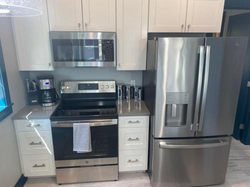 a kitchen with stainless steel appliances and white cabinets at Modern Cottage in the Heart of Charlevoix in Charlevoix