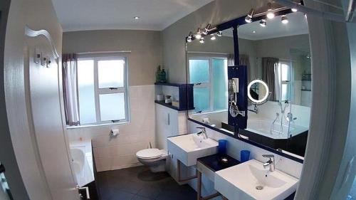 a bathroom with two sinks and a toilet and a mirror at Knysnaviews Guest House in Knysna