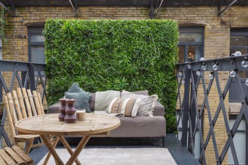 a patio with a couch and a table and a green hedge at Exclusive Penthouse- 85 Inch Huge TV in Bradford