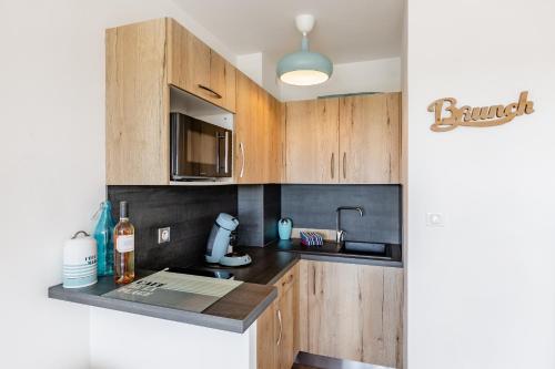 une cuisine avec des armoires en bois et un évier dans l'établissement Les balcons de Bandol Centre ville avec vue mer et face à la plage, à Bandol