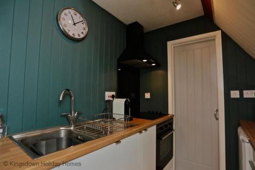 uma cozinha com um lavatório e um relógio na parede em Chalet Fortysix em Deal