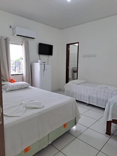 Duas camas num quarto branco com um espelho. em Hotel Monte Arau em Boa Vista