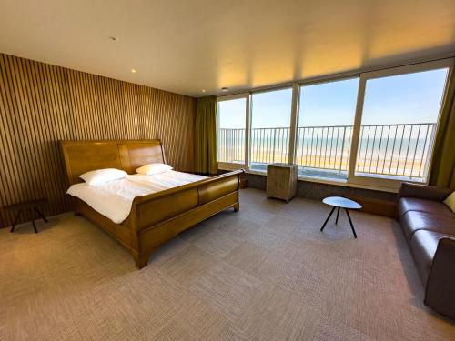 een slaapkamer met een bed, een bank en ramen bij Novo panoramic sea view in De Panne