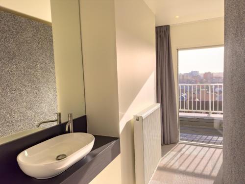 a bathroom with a sink and a balcony at Novo panoramic sea view in De Panne