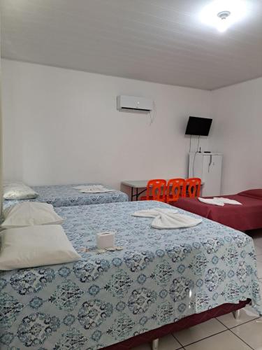 a bedroom with two beds and a red chair at Hotel Monte Arau in Boa Vista