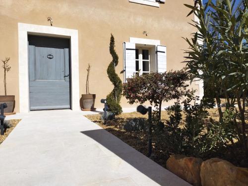 a house with a blue door and some plants at Le mas de Roussillon chambre d'hôtes in Roussillon