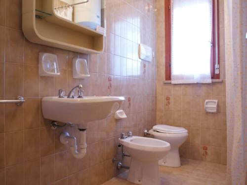 La salle de bains est pourvue d'un lavabo et de toilettes. dans l'établissement Cozy apartment in elegant resort - Beahost, à Bibione